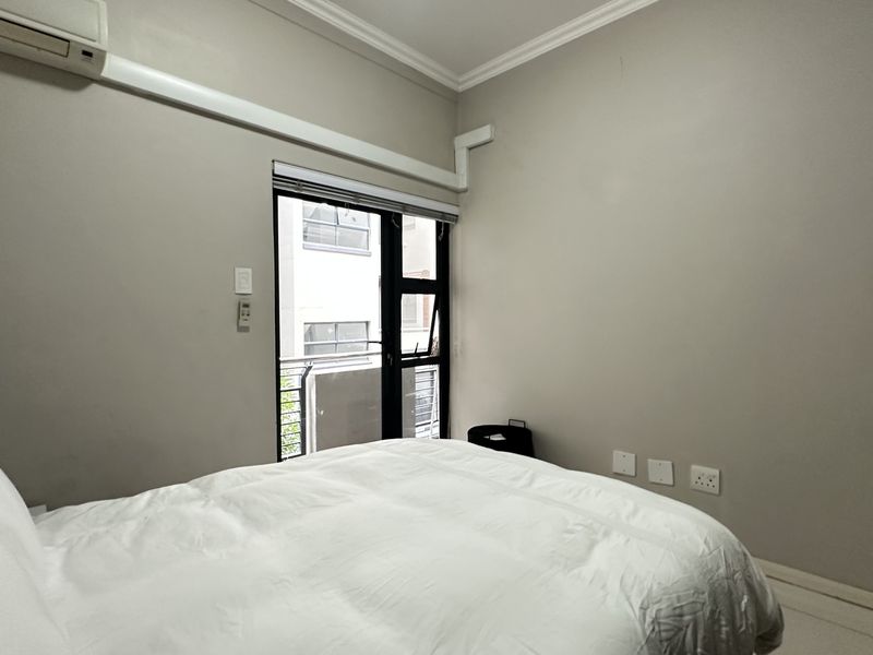 A bedroom featuring neutral walls, coving, a split-system air conditioner, and a sliding glass door providing natural light.