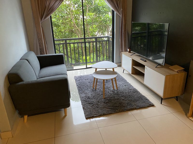 A modern living room featuring large sliding glass doors that open onto a balcony with lush greenery views and polished tiled flooring.