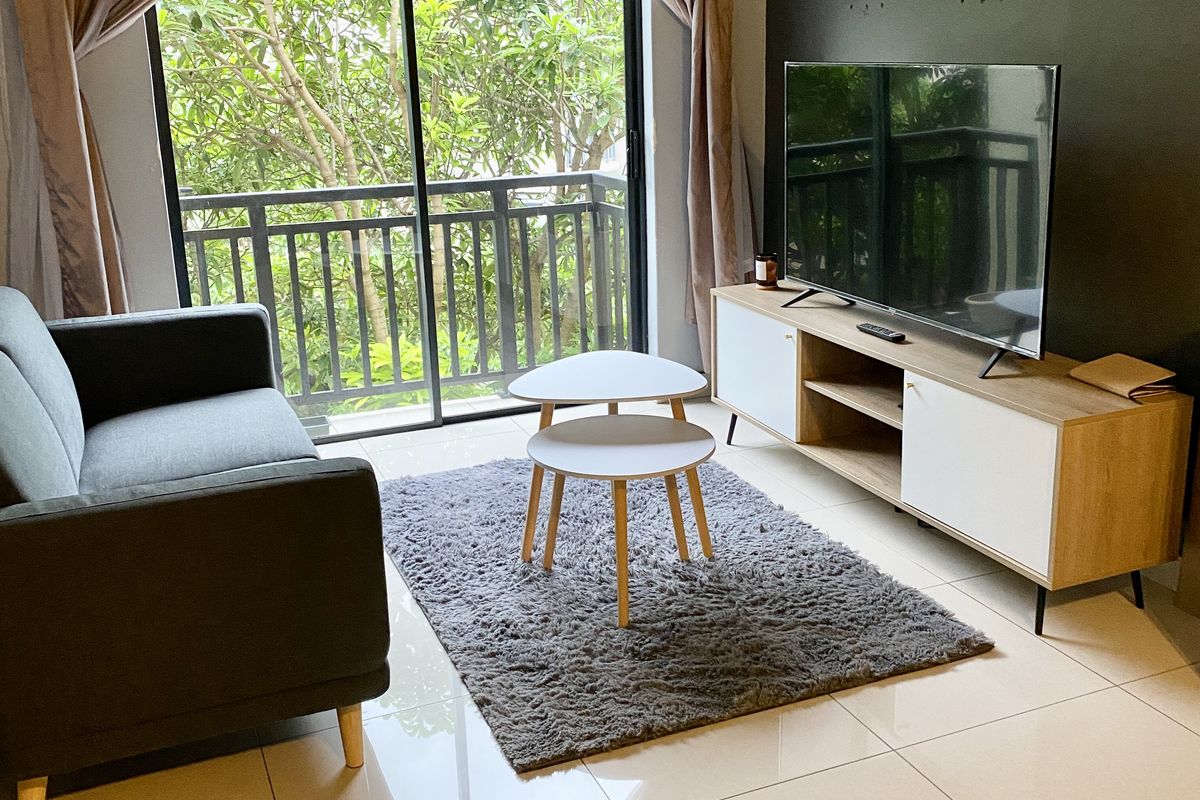 A bright living room featuring large sliding glass doors leading to a balcony, polished tile flooring, and a modern accent wall.