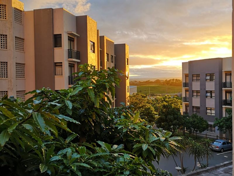 A scenic view overlooking the apartment complex grounds and surrounding landscape during a vibrant sunset.