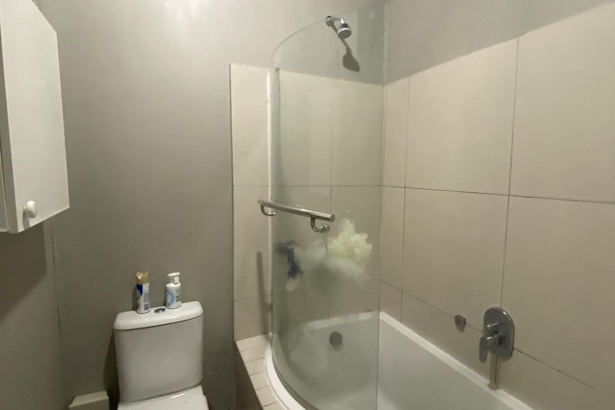 Compact bathroom featuring a combined shower and bathtub, tiled walls, and a standard toilet and basin setup.