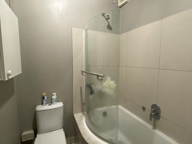 Compact bathroom featuring a combined shower and bathtub, tiled walls, and a standard toilet and basin setup.