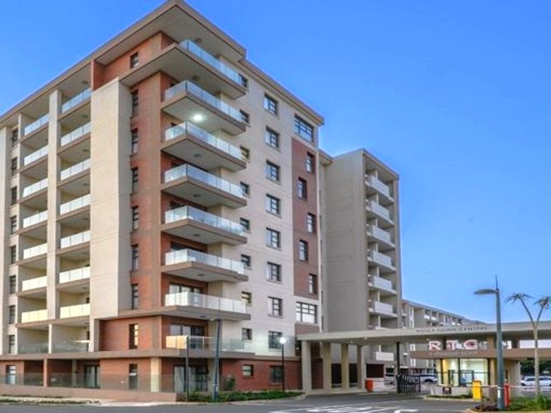 A modern multi-story apartment complex featuring contemporary architectural design, glass balconies, and a secure gated entrance.