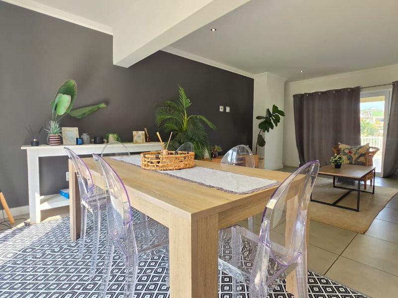 Spacious open-plan living and dining area featuring neutral tiled flooring, recessed downlighting, and a sliding glass door providing access to the outdoor space.