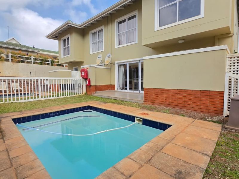 Rear exterior view of the townhouse featuring a private swimming pool, paved patio area, and direct access via sliding glass doors.