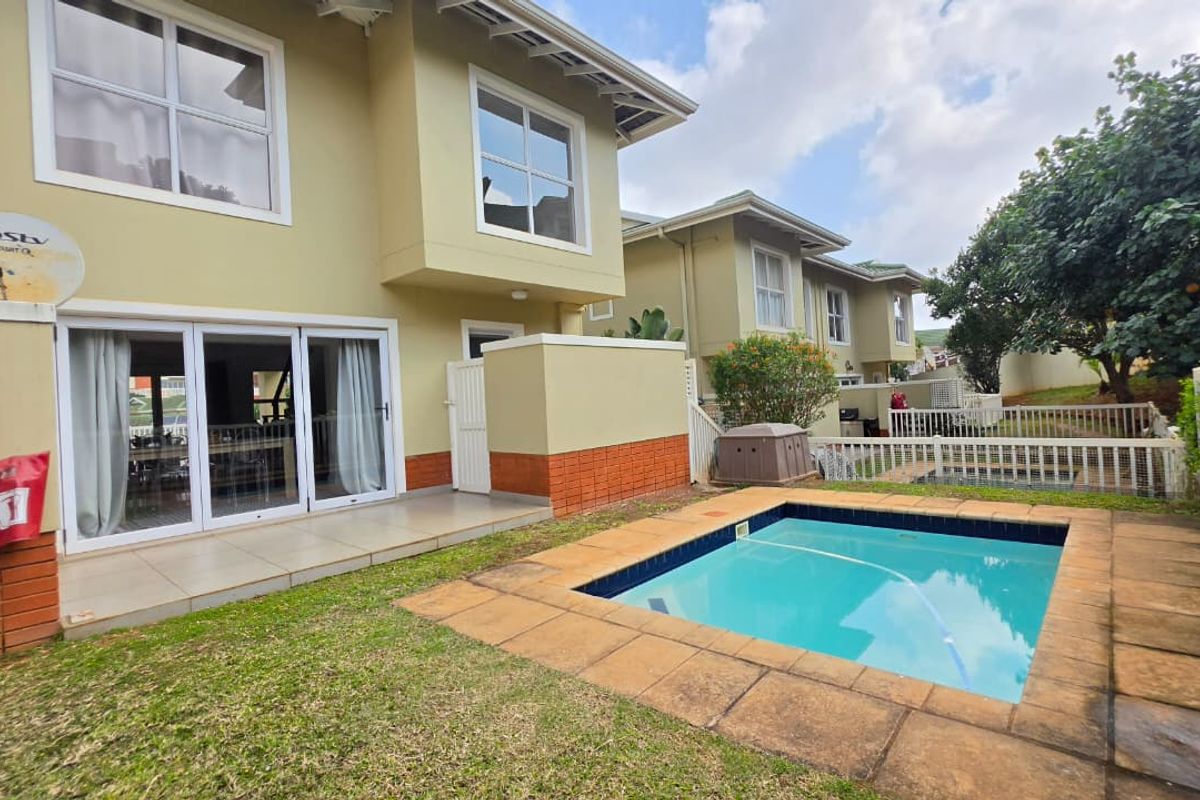 Rear exterior view of the townhouse featuring a private swimming pool, tiled patio area, and direct access to the living space via sliding glass doors.