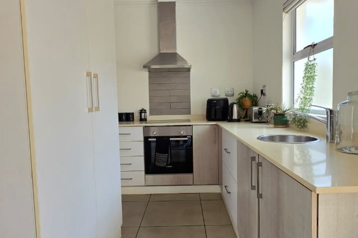 A modern, well-maintained kitchen featuring light-toned cabinetry, stone countertops, stainless steel appliances, and tiled flooring with recessed lighting.