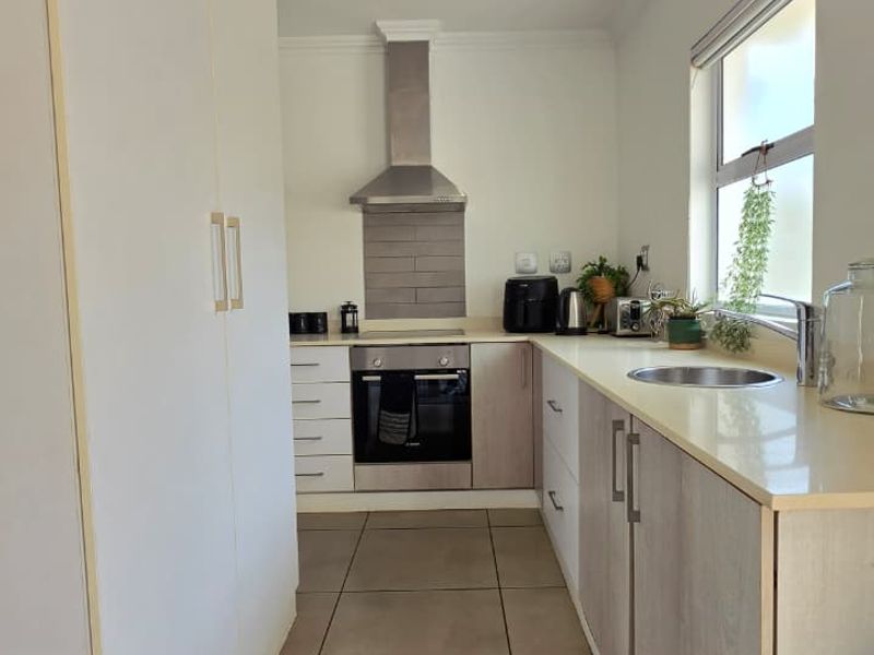 A modern, well-maintained kitchen featuring light-toned cabinetry, stone countertops, stainless steel appliances, and tiled flooring with recessed lighting.