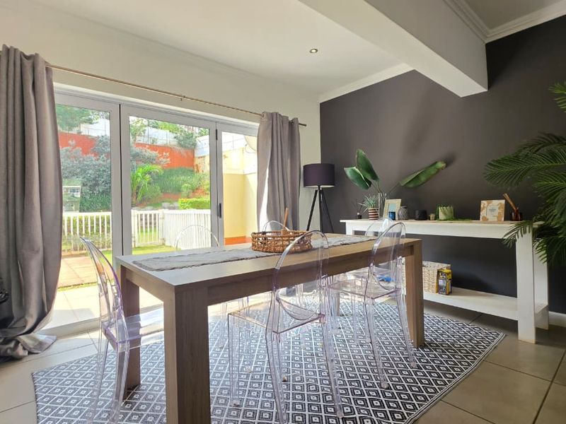 Bright dining area featuring tiled floors, modern recessed lighting, and large sliding glass doors providing direct access to the rear patio and garden.