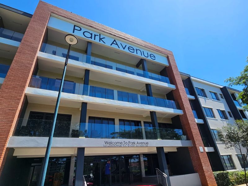 Exterior view of the Park Avenue apartment building, showcasing modern brick architecture, glass-fronted balconies, and a clear entrance area.
