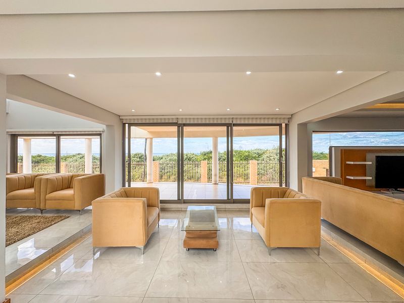 Spacious open-plan living area featuring polished marble-look flooring, recessed downlighting, and large sliding glass doors opening to a scenic outdoor patio.