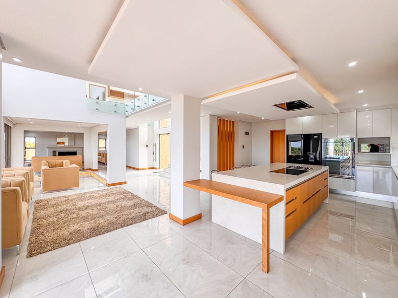 Spacious open-plan living area featuring a modern kitchen with a central island, high-end built-in appliances, and sleek porcelain flooring throughout.