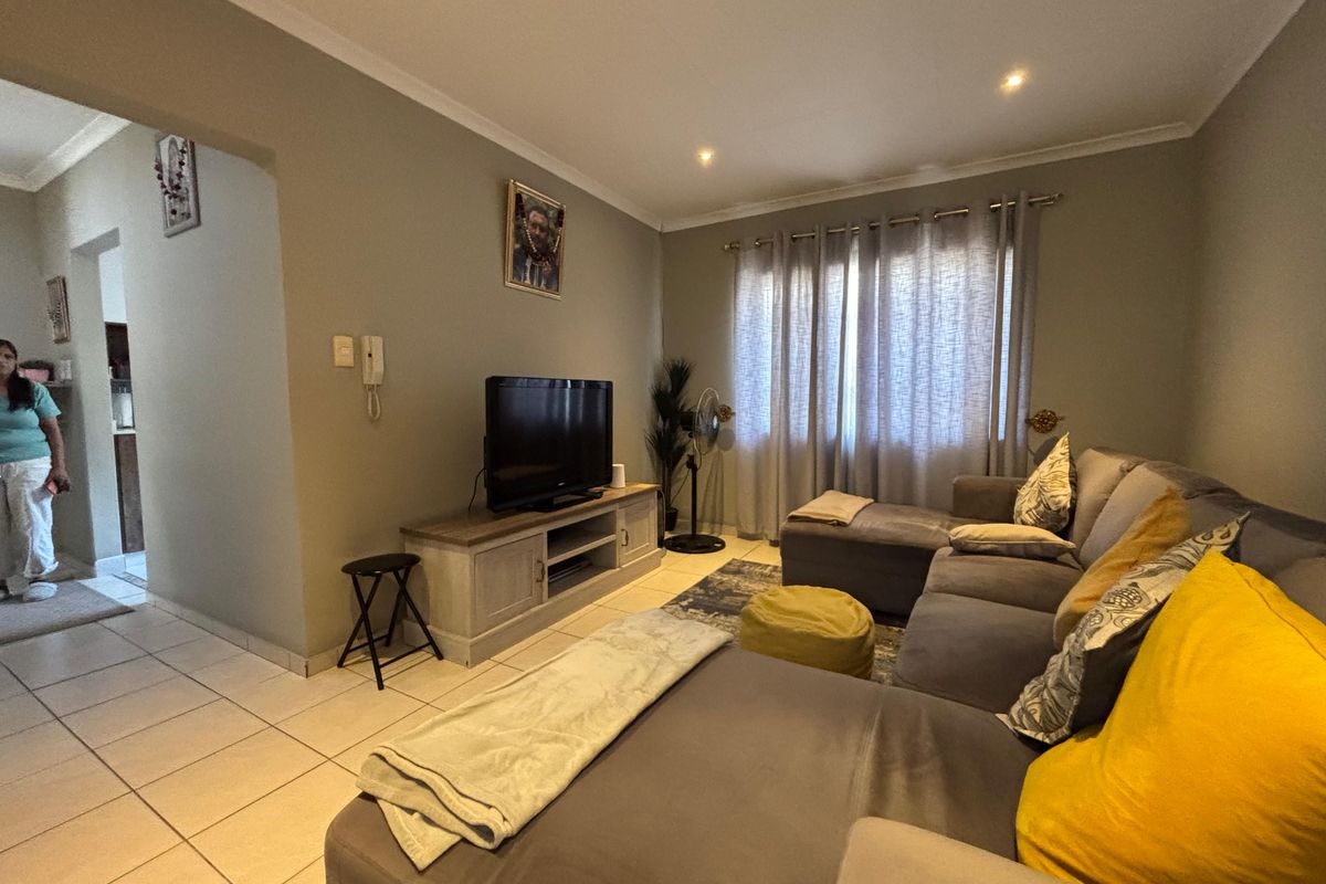 A comfortable living room featuring neutral wall tones, tiled flooring, and recessed downlighting, providing a functional and inviting space.