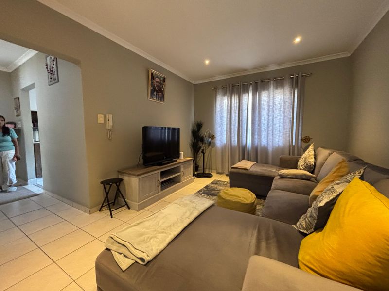A comfortable living room featuring neutral wall tones, tiled flooring, and recessed downlighting, providing a functional and inviting space.