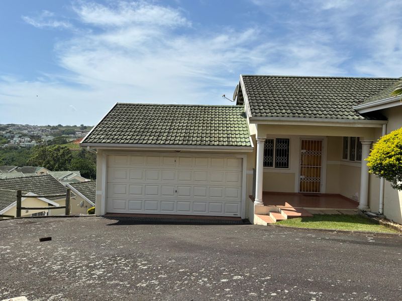 Front exterior view of the townhouse featuring a single garage, covered entrance porch, and a paved driveway with surrounding neighborhood views.