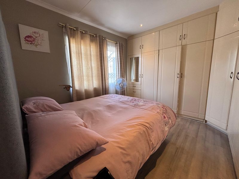 A functional bedroom featuring extensive built-in cabinetry, laminate flooring, and neutral wall tones, offering practical storage and a comfortable living space.