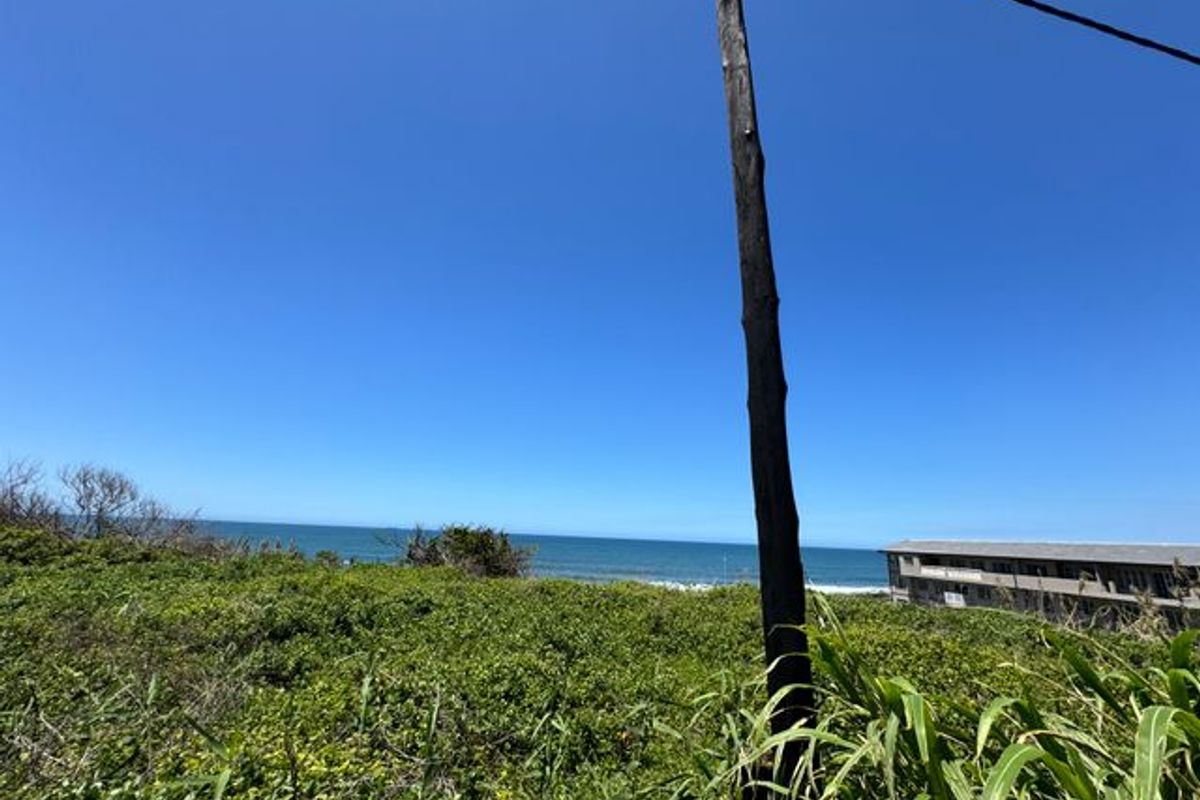A scenic view of the ocean and coastline from the vacant residential land, featuring natural vegetation and an existing utility pole.