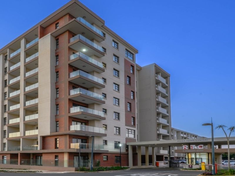 Modern multi-story apartment complex featuring a brick and render facade, glass-fronted balconies, and a secure gated entrance.
