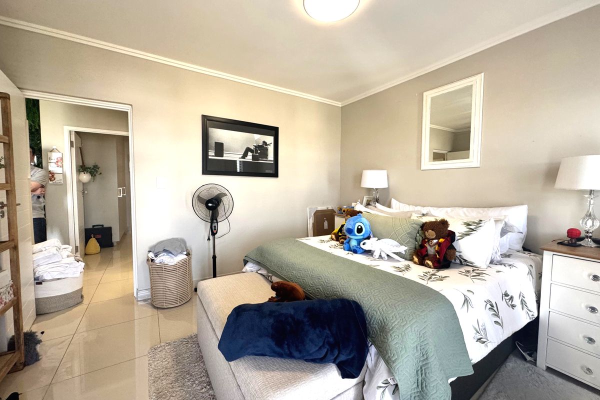 A well-maintained bedroom featuring neutral wall tones, tiled flooring, and a coved ceiling, providing a comfortable and functional living space.