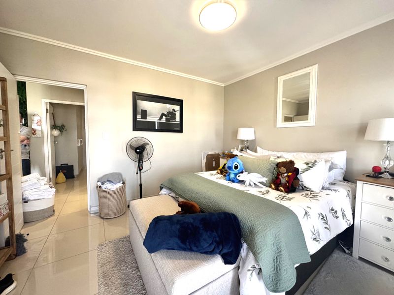 A well-maintained bedroom featuring neutral wall tones, tiled flooring, and a coved ceiling, providing a comfortable and functional living space.