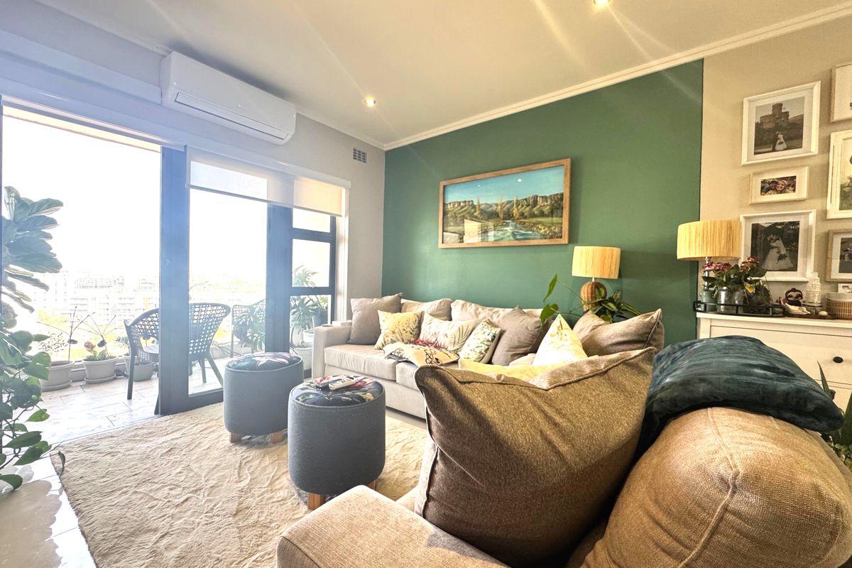 A bright and well-maintained living room featuring a split-system air conditioner, recessed lighting, and direct access to an outdoor balcony through sliding glass doors.