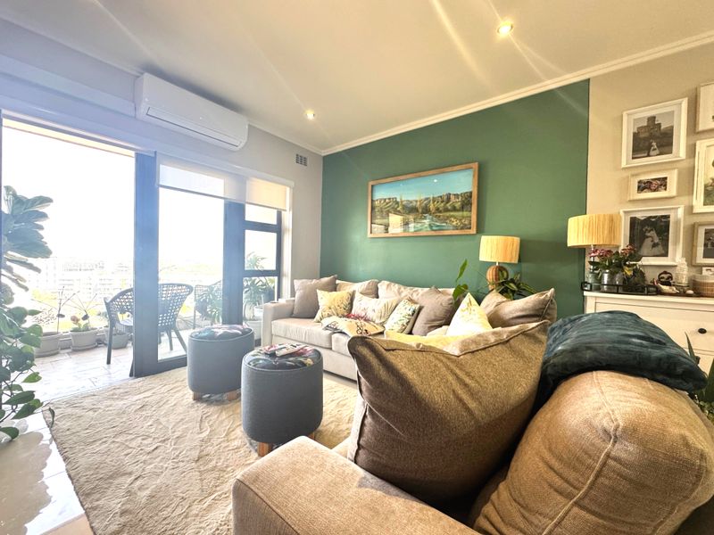 A bright and well-maintained living room featuring a split-system air conditioner, recessed lighting, and direct access to an outdoor balcony through sliding glass doors.