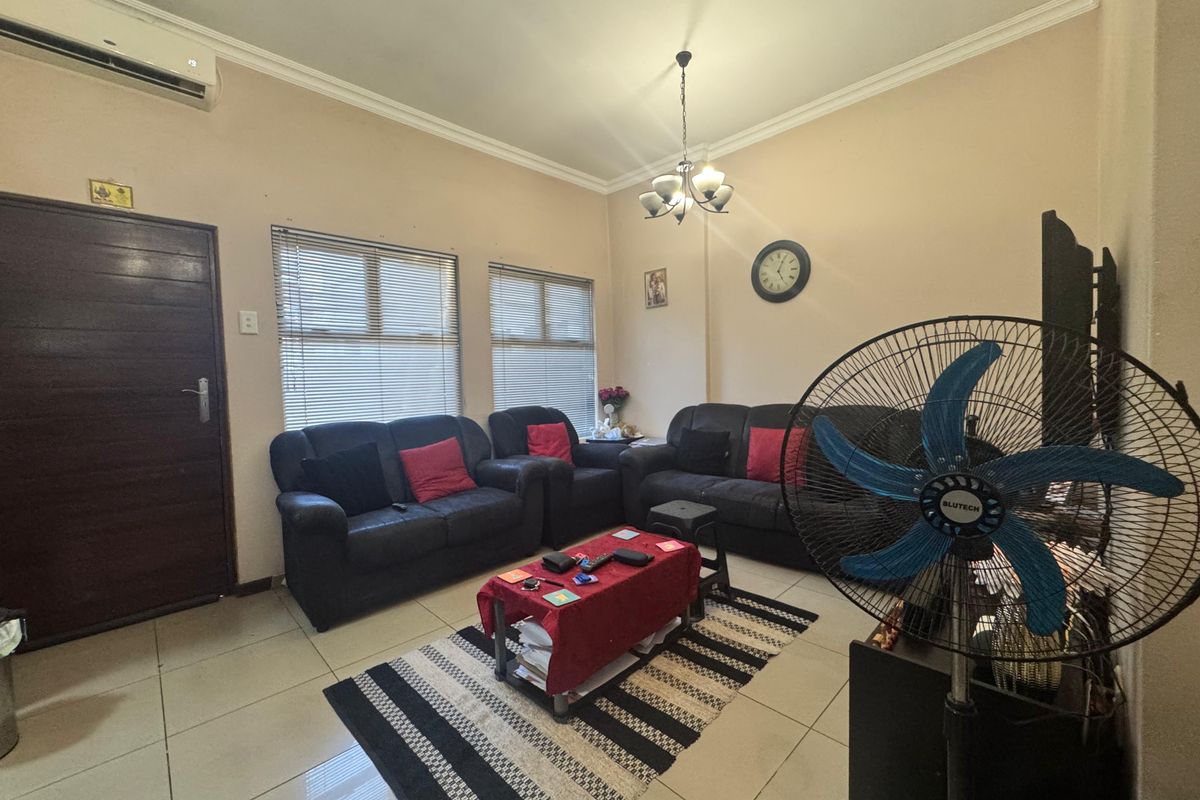 A living room featuring tiled flooring, a split-system air conditioner, and venetian blinds, providing a functional and comfortable space.