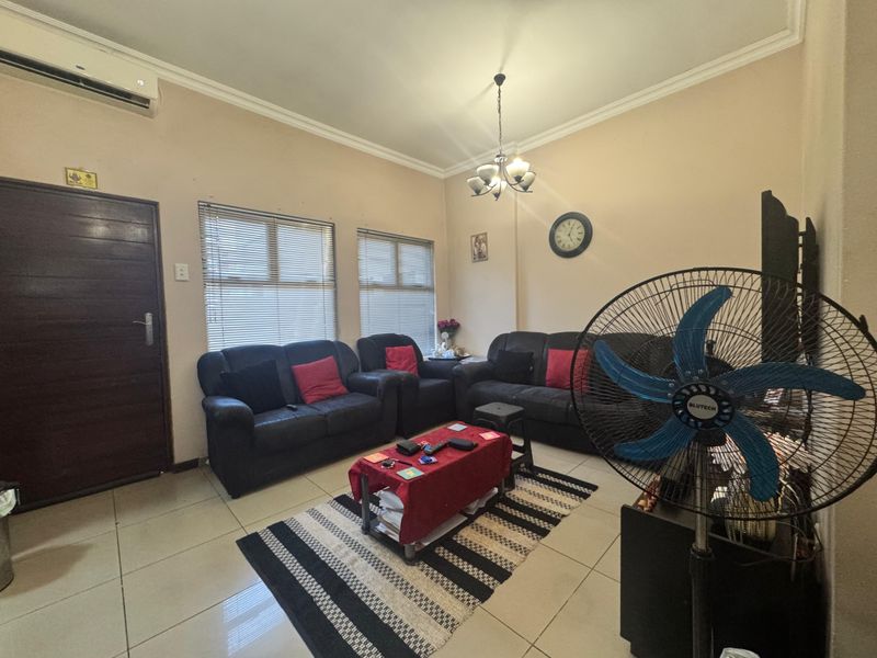 A living room featuring tiled flooring, a split-system air conditioner, and venetian blinds, providing a functional and comfortable space.