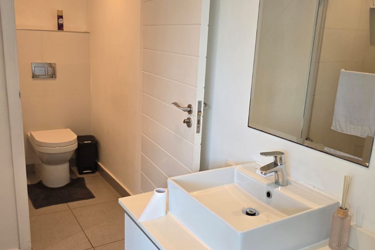 A modern bathroom featuring a wall-hung toilet with a concealed cistern, a vessel sink vanity, and a large wall mirror.