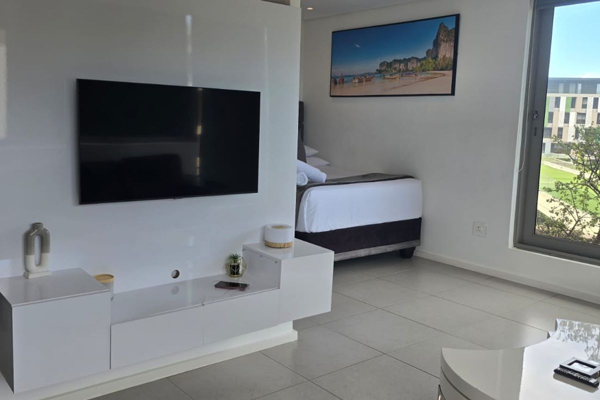 Modern bedroom featuring tiled flooring, a built-in media console, and a large sliding glass door providing natural light and exterior views.