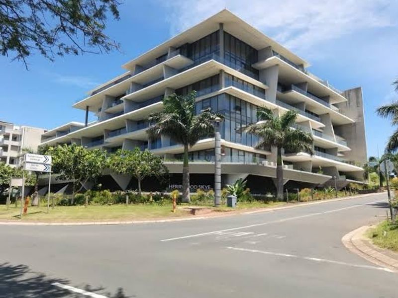 Modern multi-story apartment building featuring a striking architectural design with tiered glass balconies and landscaped surroundings.