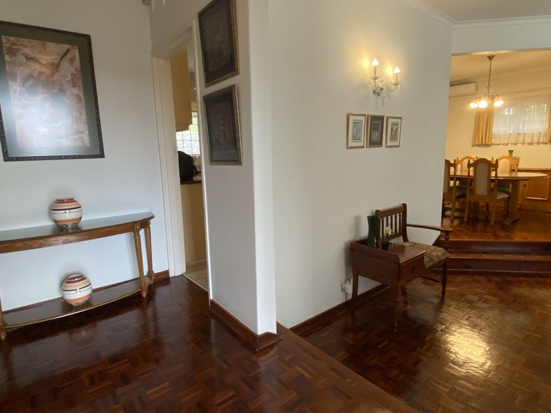 Entrance foyer featuring polished parquet flooring and wall sconce lighting, providing a warm transition into the adjacent dining area.