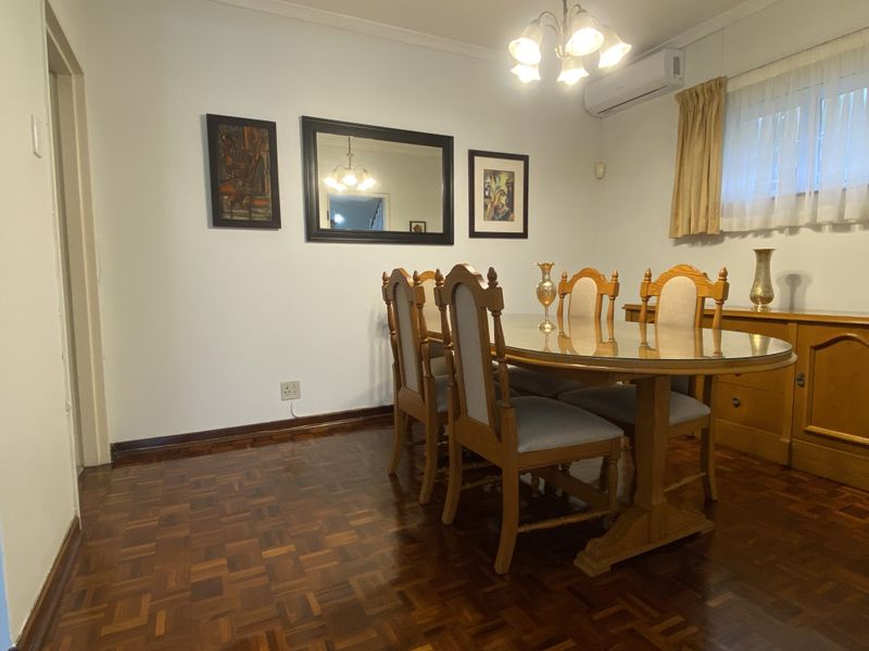 A well-maintained dining room featuring classic parquet flooring, a split-system air conditioner, and traditional crown molding.