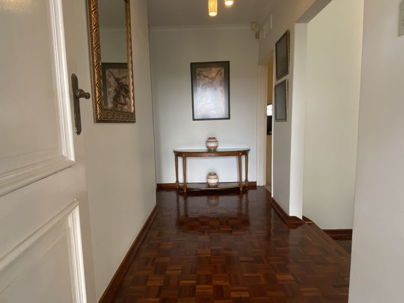 A well-maintained entrance hallway featuring polished parquet flooring and neutral wall finishes, providing a warm and welcoming transition between living spaces.
