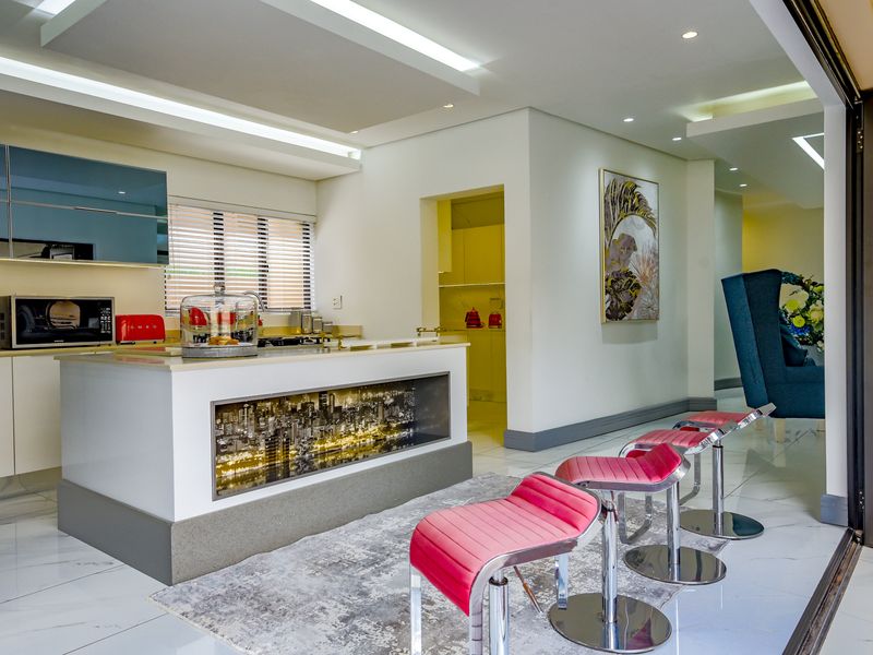 Modern kitchen featuring a central island with integrated cabinetry, stone countertops, recessed lighting, and seamless access to an adjoining scullery and outdoor area.