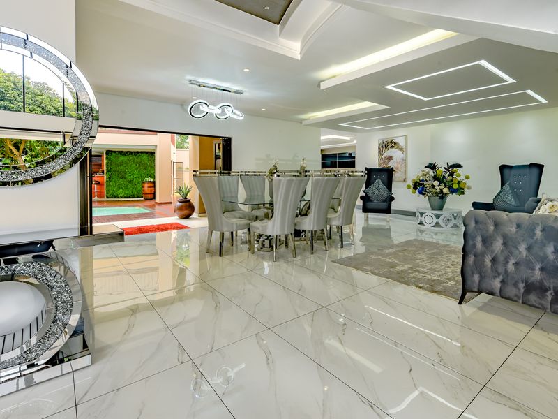 Spacious open-plan living and dining area featuring high-gloss marble-look floor tiles, modern recessed ceiling lighting, and seamless access to the outdoor patio.