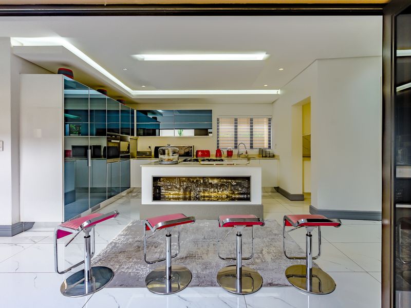 Modern kitchen featuring a central island, high-gloss cabinetry, integrated appliances, and sleek tiled flooring with recessed lighting.