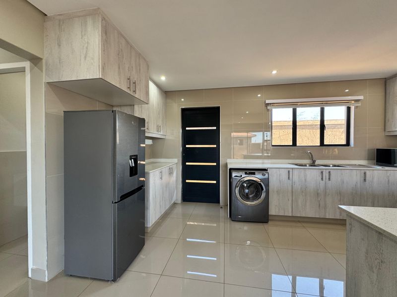 Modern kitchen featuring light wood-grain cabinetry, stone countertops, tiled backsplash, and high-gloss floor tiles with integrated appliance spaces.