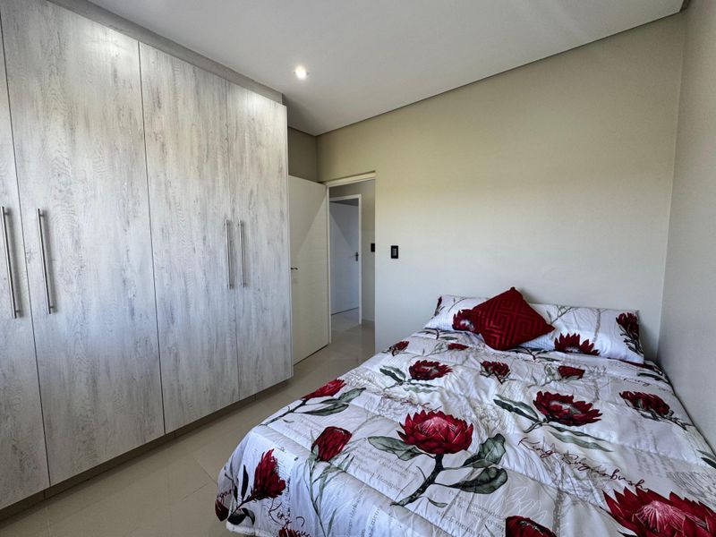 A well-maintained bedroom featuring modern built-in cupboards, neutral wall finishes, and tiled flooring, offering a clean and functional living space.