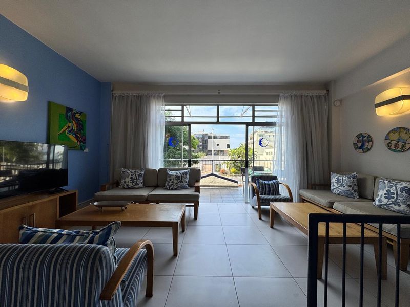 Spacious living room featuring tiled flooring and large sliding glass doors that open onto a balcony, providing natural light and outdoor access.
