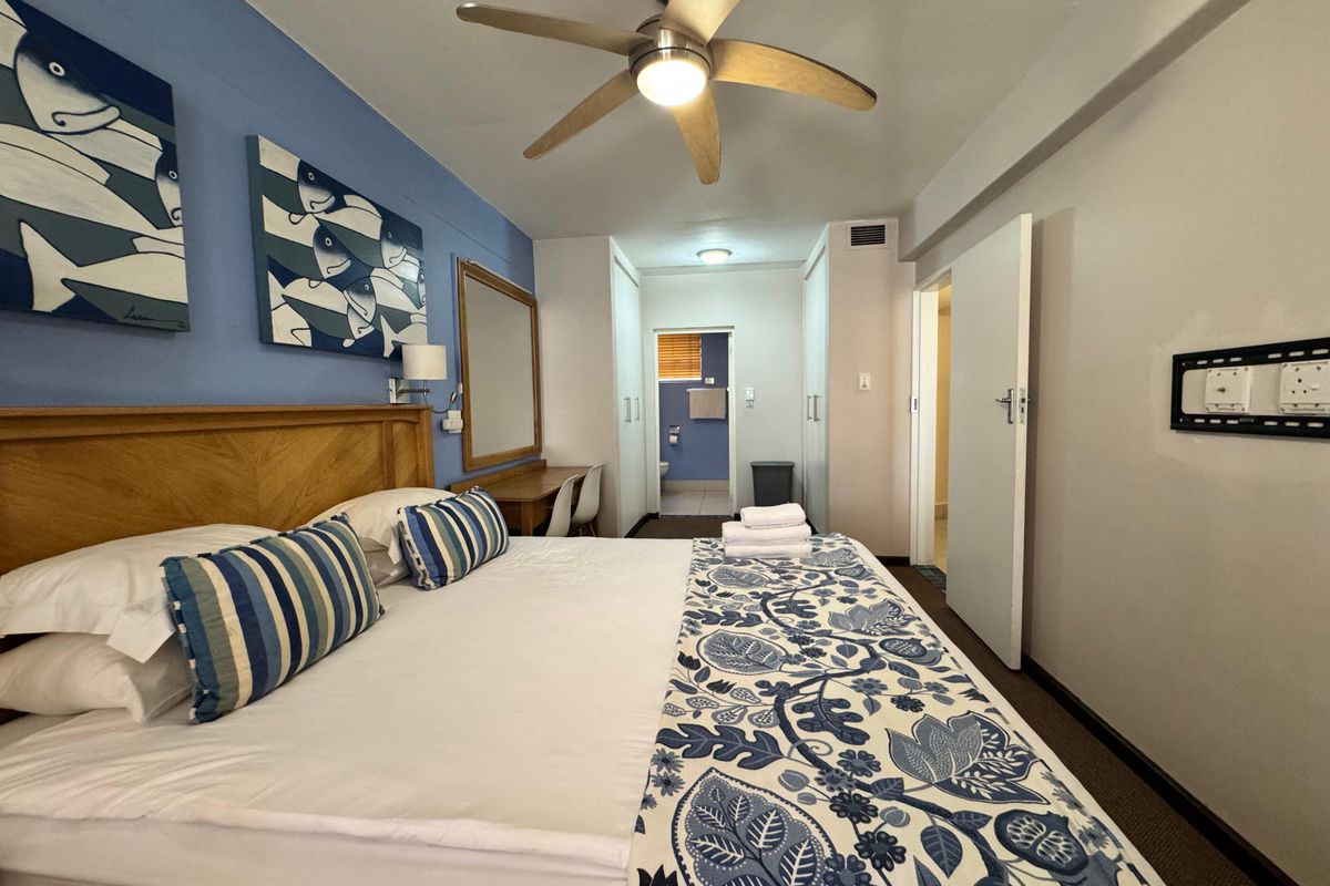 A well-maintained bedroom featuring a ceiling fan, built-in cupboards, and an integrated vanity area with direct access to an en-suite bathroom.
