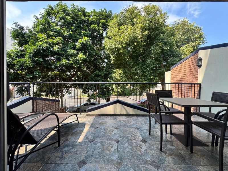 A spacious balcony featuring tiled flooring, a metal balustrade, and a brick feature wall, offering an outdoor area for relaxation.