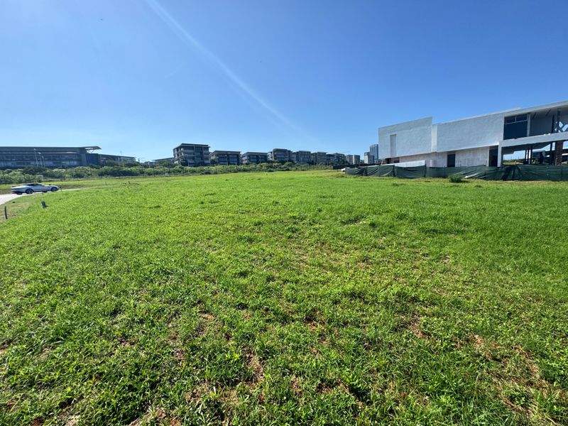 A spacious, level residential vacant land plot featuring established grass cover and perimeter fencing, situated in a developing estate.
