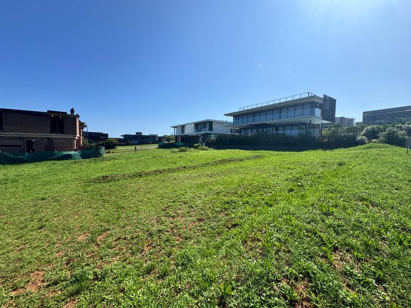 A view of a vacant residential plot with surrounding modern homes in a developed estate setting.