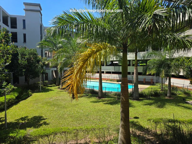 A well-maintained communal swimming pool area surrounded by landscaped gardens and apartment building facades.