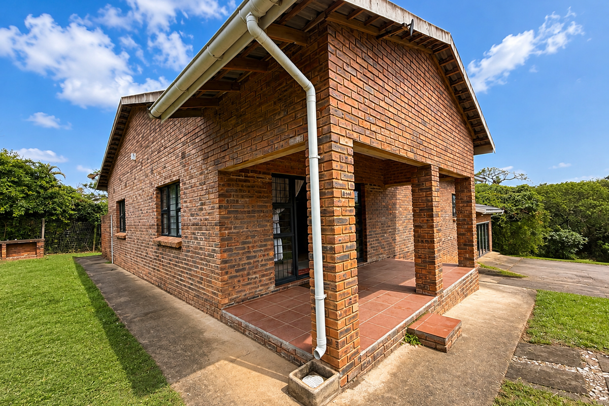 Rear view of a face brick house featuring a covered patio with tiled flooring, brick pillars, and an adjacent built-in braai area.
