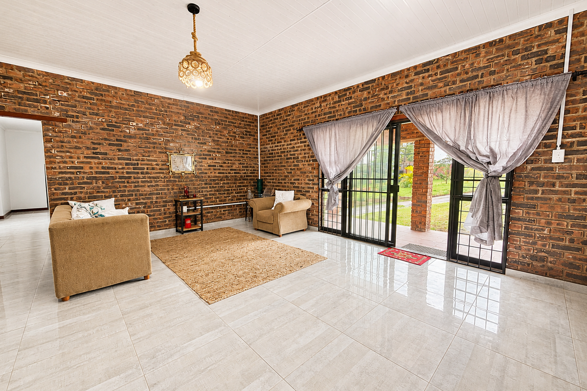 Spacious living room featuring exposed brick walls, polished tile flooring, and large sliding glass doors providing direct access to the outdoor patio area.