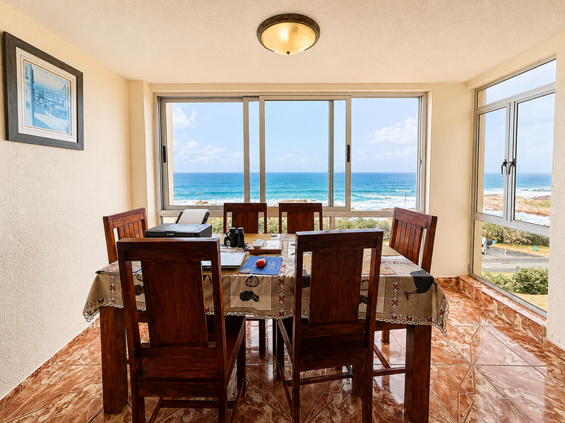Dining area featuring tiled flooring and expansive windows offering panoramic ocean views, providing a bright and scenic space for meals.