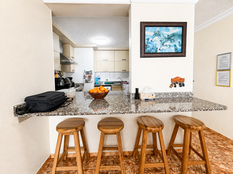 Open plan kitchen featuring a granite breakfast bar, built-in cabinetry, and tiled flooring, creating a functional space for dining and food preparation.