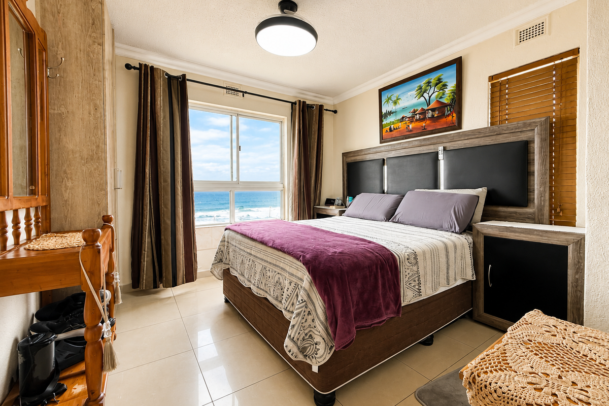 A well-maintained bedroom featuring tiled flooring, a ceiling light fixture, and a sliding window offering a direct view of the ocean.